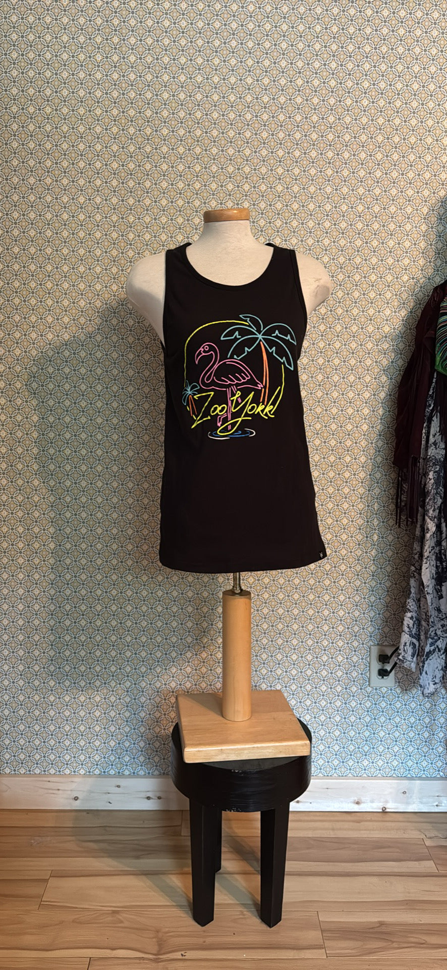 A black sleeveless tank top.The tank top features a colorful graphic of a pink flamingo, a palm tree, and the words 'Zoo York' in yellow script.