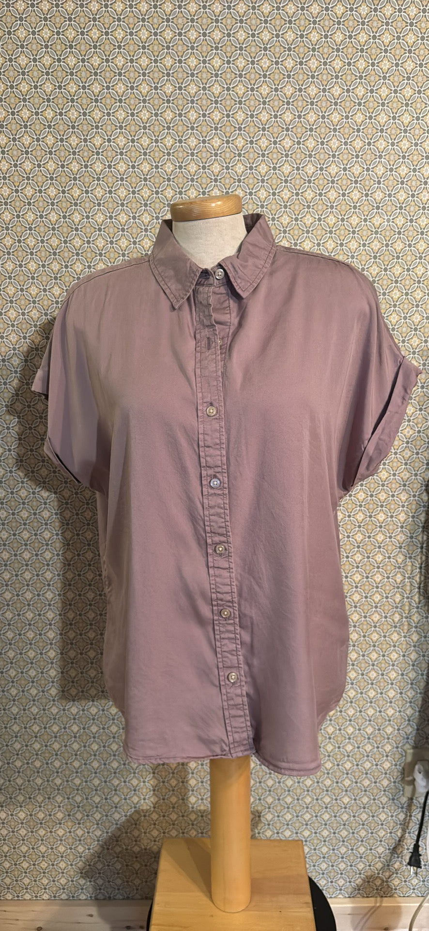 A short-sleeve button-up shirt in a dusty mauve or muted purple colorbackground.