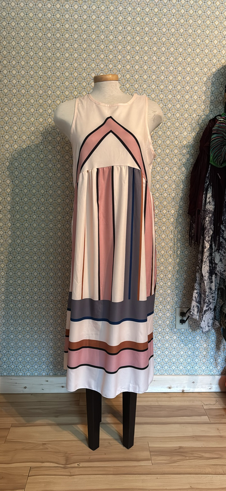 A sleeveless midi dress featuring vertical stripes in pink, navy blue, and white with a chevron pattern at the neckline