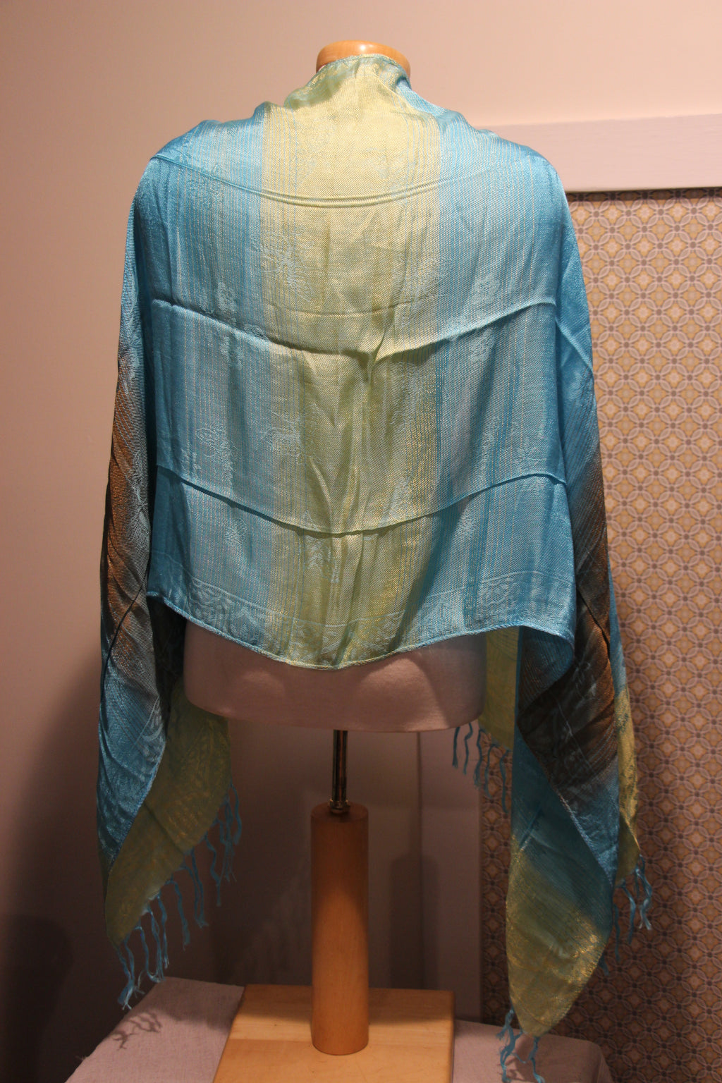 A lightweight woven shawl with vertical stripes of light blue, pale yellow-green, and brown. The shawl features fringed edges.
