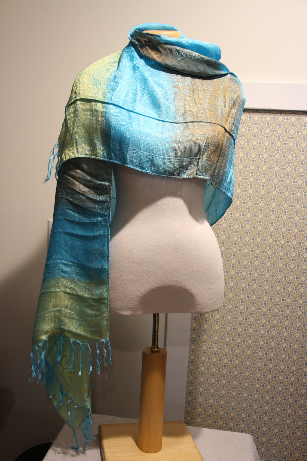 A consignment lightweight fringed scarf, featuring a gradient color transition from bright turquoise blue to bronze and yellow-green. 