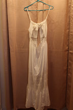 A white sleeveless maxi dress with thin straps, a bow detail at the neckline, and lace panels. A Consignment boutique, Size L White Halter Dress with Button Front Lace Panels and Gathered Hem.
