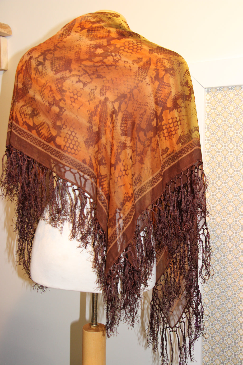 A  consignment orange, brown and green patterned shawl with long dark brown fringe.