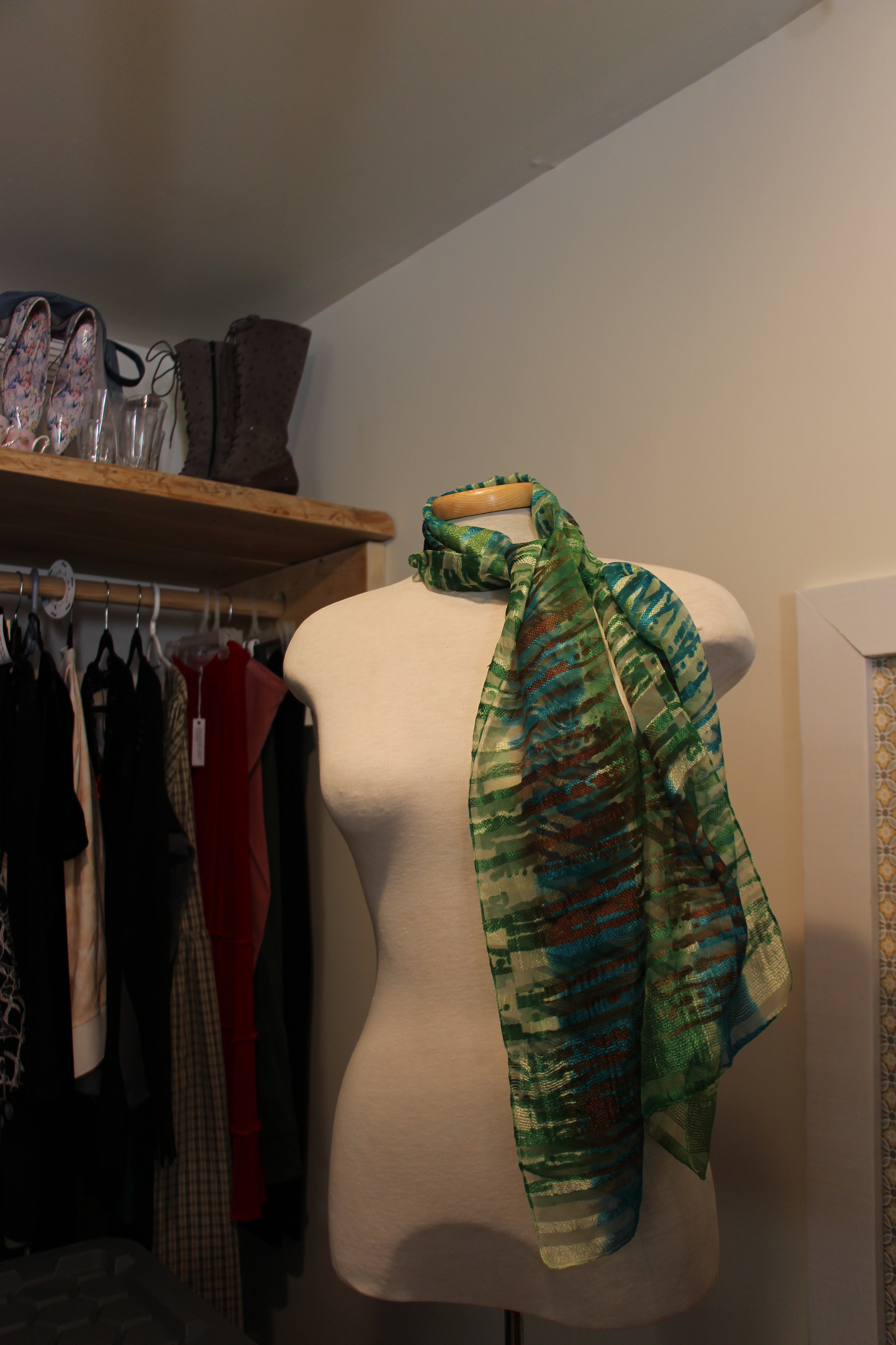 A consignment lightweight  scarf with a green, blue, and brown abstract pattern.