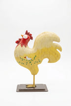 A charming piece of Americana nostalgia: this Russ Berrie &amp; Co. hand-painted rooster brings folk-art warmth to any room. The soft-hued resin body showcases intricate hand-painted details—rustic red comb, delicate green vine work, and a sweet companion bird cradling a heart—all anchored on a sturdy metal display stand. Perfect for farmhouse, cottage, or eclectic vintage collectors.