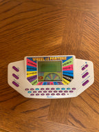A vintage Fisher-Price 'Wheel of Fortune' handheld game console resting on a wooden parquet floor.